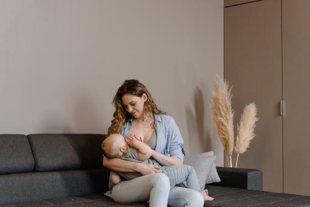 Woman breastfeeding her baby, sitting on a sofa