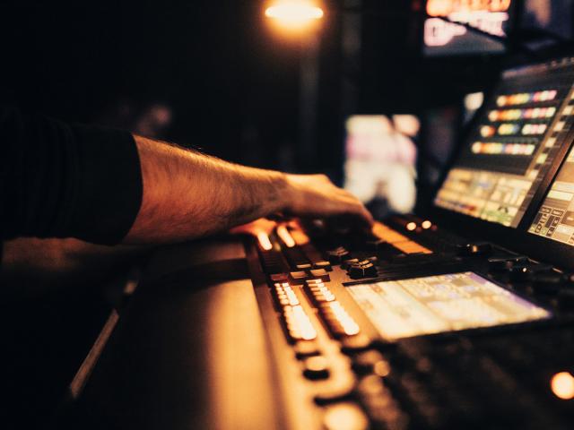 A close up of someone's hands operating a mixing desk