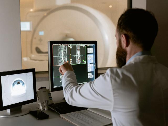 A man in a white coat looking at MRI images