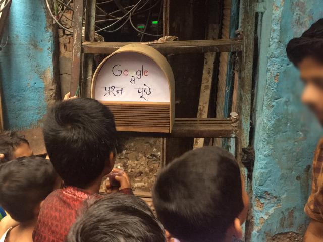 Children looking at a prototype of a smart speaker in India
